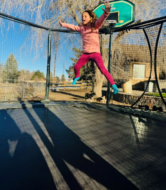 Child in pink leaping in air on trampoline