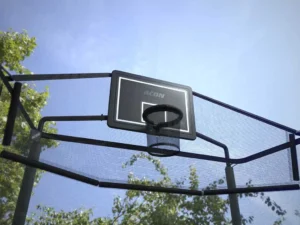 A net around a round trampoline with a basketball hoop.